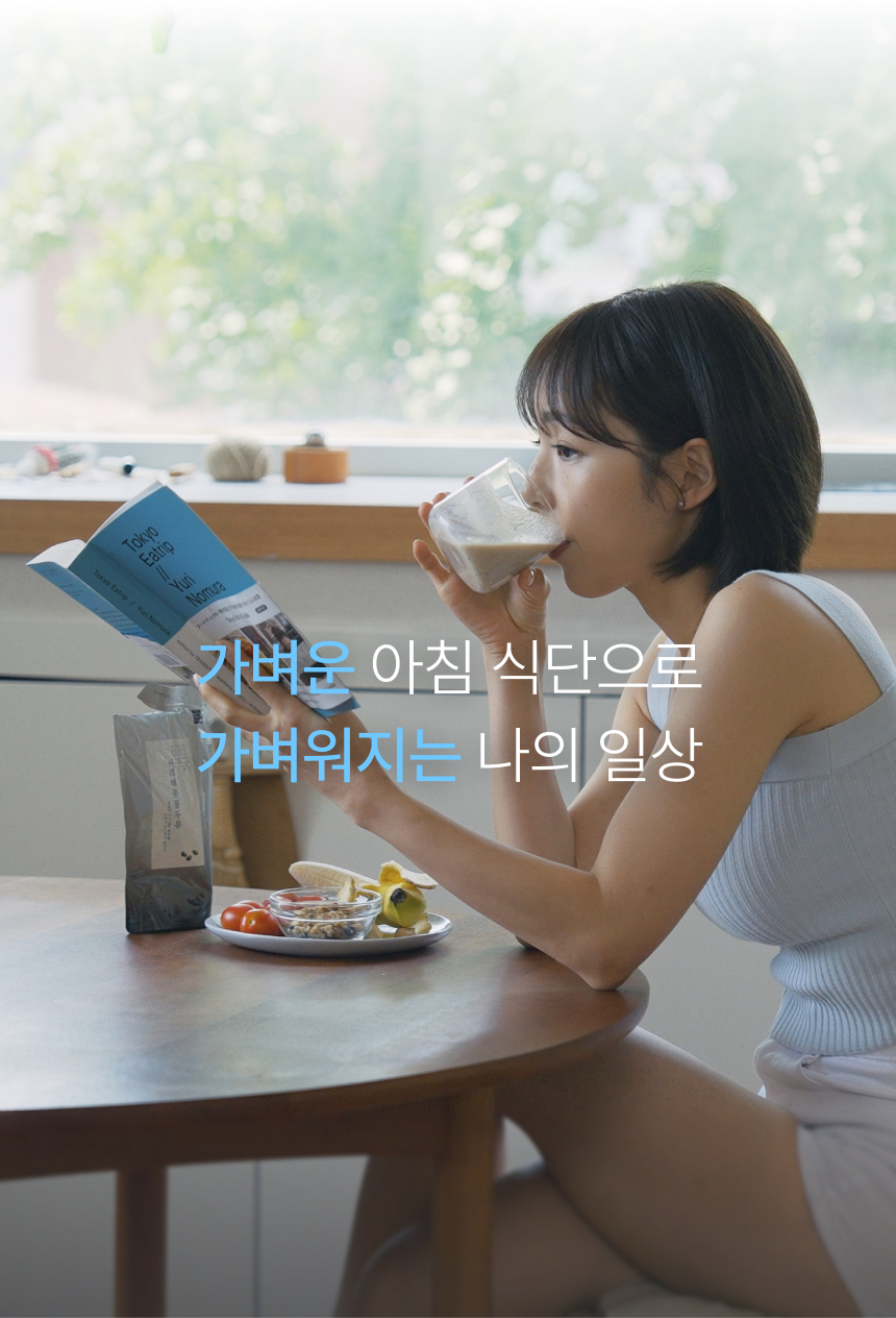 가벼운 아침 식단으로 가벼워지는 나의 일상 - 창가 테이블에서 책을 보며 서리태콩물두유를 마시는 모습